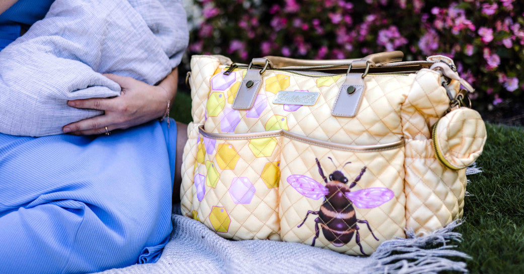 Colourful vibrant baby diaper nappy bag. Mother sitting on picnic rug with baby next to the best shoulder tote diaper nappy bag